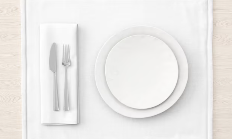 plates, fork, knife, and white napkins on wooden table