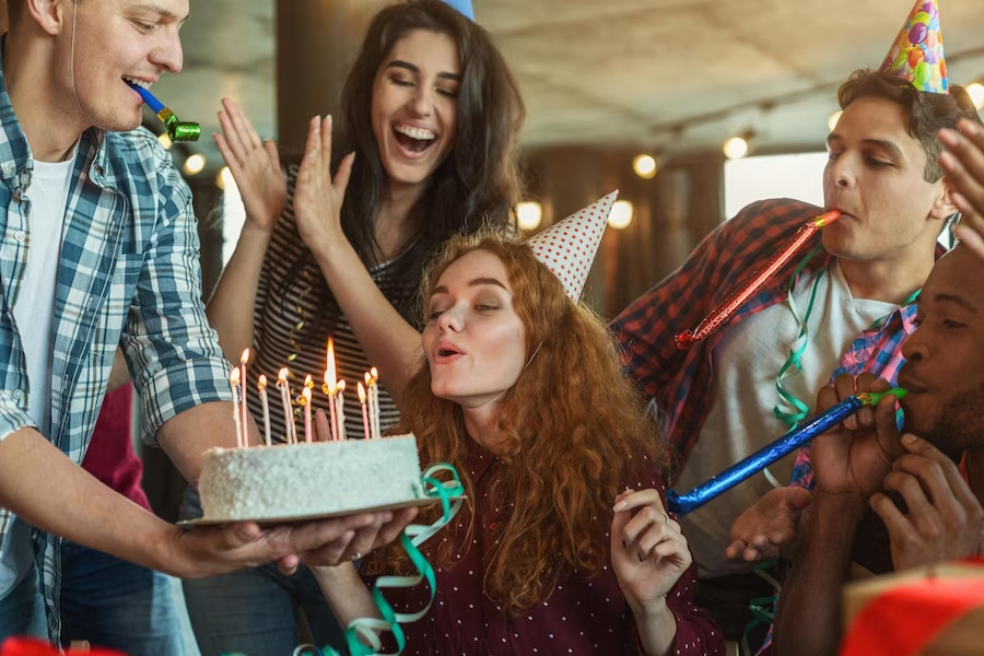 celebrant blowing out candle on cake with friends