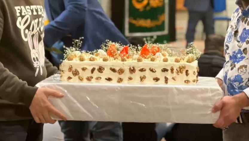 Two individuals holding a half sheet cake