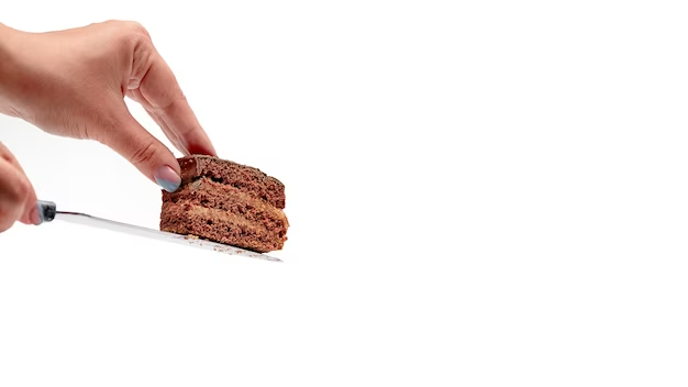 A cake slice on a knife with a hand preventing it from falling