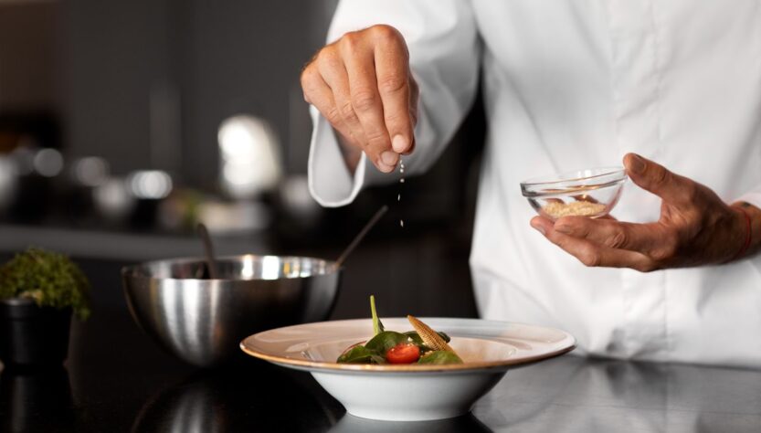 The chef adds seasoning to the dish